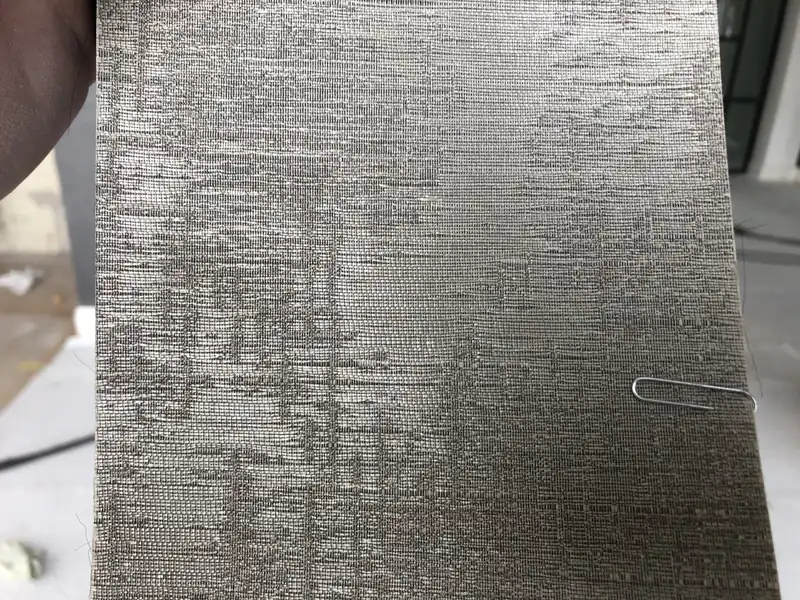 Close-up van een baan behang met een zilverkleurige, fijn gestreepte structuur